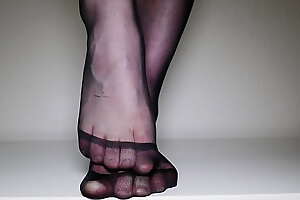 Feet in black pantyhose tights